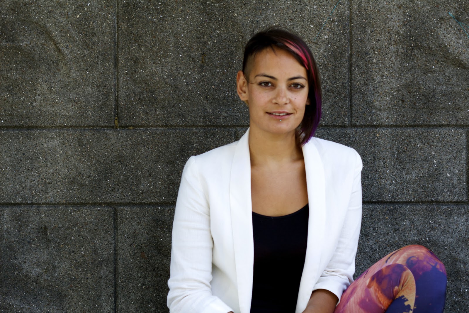 Zarinah, a light skinned female presenting person wearing a white blazer with a black shirt underneath